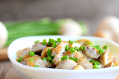 Ekşi krema ve bir kase taze yeşil soğan ile kavrulmuş mantar. Vejetaryen yemek. Kolay sağlıklı mantar tarifi. Taze mantar, yeşil soğan vintage ahşap masa üzerinde. Portre