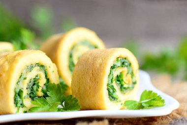 Peynir ve maydanoz omlet bir plaka üzerinde rulo. Ev kızartılmış omlet rendelenmiş peyniri ve ince kıyılmış maydanoz ile alır. Lezzetli vejetaryen yumurta kahvaltı tarifi. Rustik tarzı. Portre
