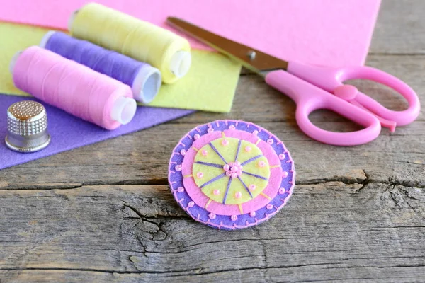 Felt round flower decorated with beads. Handmade cute round felt flower, scissors, thread, colored felt sheets, thimble on vintage wooden background. Simple and quick kids sewing project — Stock Photo, Image