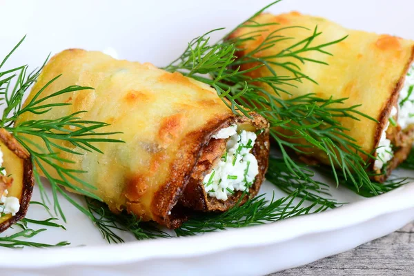 Arrotola l'idea delle zucchine fatte in casa. Rotoli di zucchine ripieni farciti con ripieno di fiocchi di latte cremosi ed erbe aromatiche su un piatto. Ricetta antipasto dietetico. Primo piano — Foto Stock