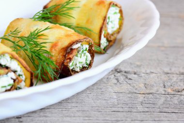 Süzme peynirli kabak alır. Kızarmış kabak bir plaka ve ahşap masa üzerinde süzme peynir ve dereotu ile alır. Güzel vejetaryen meze tarifi