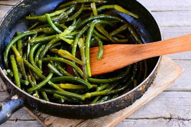 Kızarmış sarımsak oklar bir kızartma tavası ve vintage ahşap bir masa. Basit ve sağlıklı sebze yemek