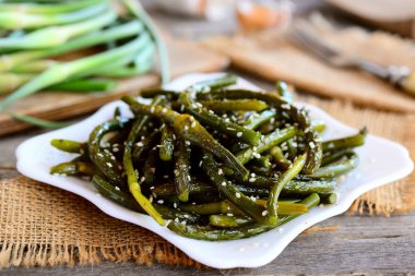 Fried genç bahar sarımsak baharat ve susam beyaz tabakta. Rustik tarzı. Sağlıklı vejetaryen yemek tarifi. Portre