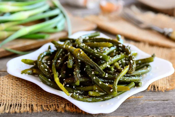 Stekt unga våren vitlök med kryddor och sesamfrön på en vit platta. Rustik stil. Hälsosam vegetarisk maträtt recept. Närbild — Stockfoto