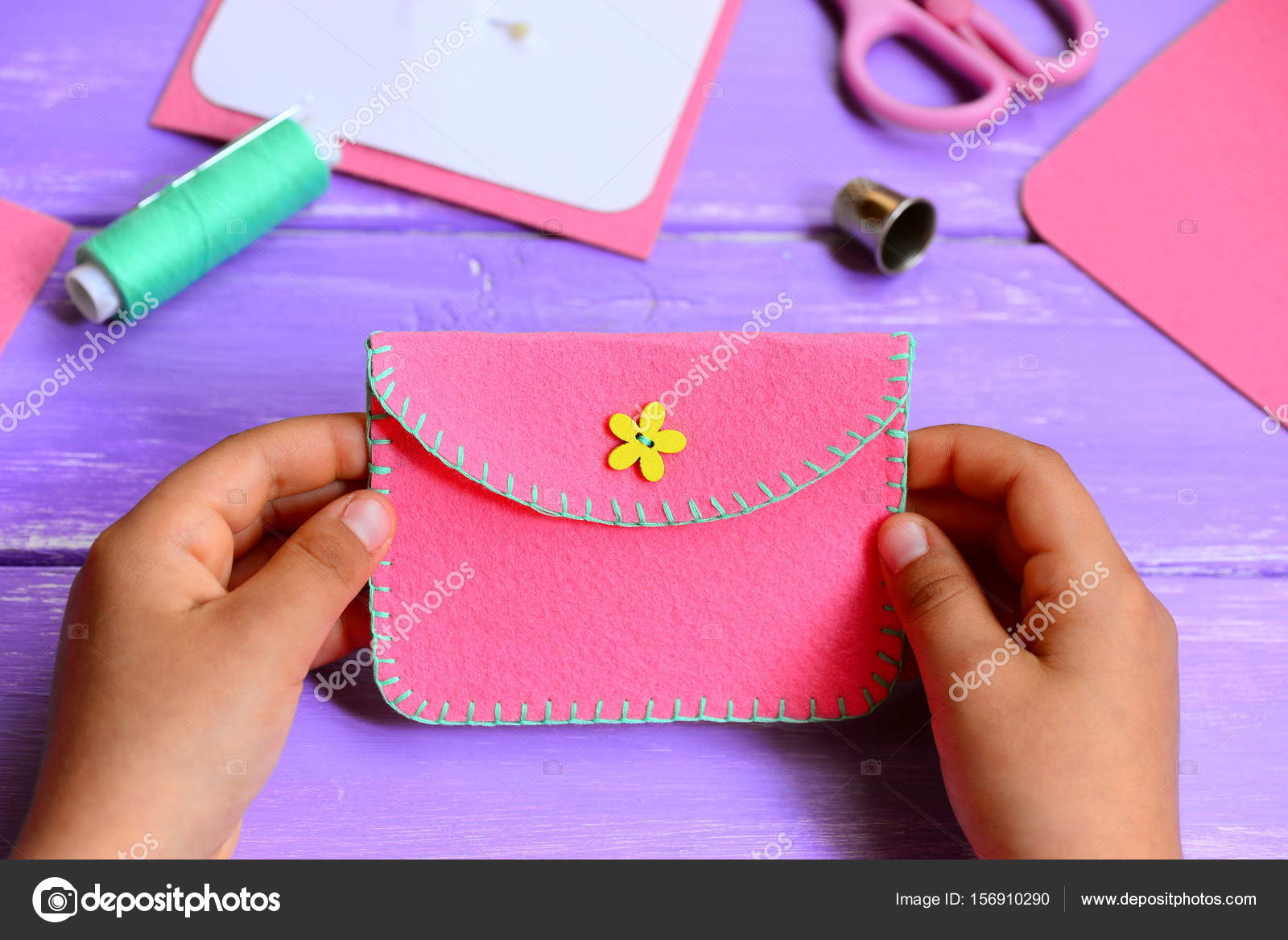 Child made a felt purse. Small child holds a pink felt purse in