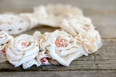 Romantic shabby chic necklace on a vintage wooden background. Beautiful flower necklace made of cotton fabric, lace ribbons and beads. Easy way to turn old fabric into jewelry. Closeup clipart