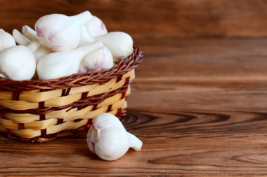 Taze beyaz sarımsak bir hasır sepet ve kopya alanı metin için bir kahverengi ahşap zemin üzerine. Genç sarımsak ampuller kavramı hasat. Portre