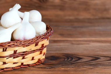 Kopya alanı metin için ahşap bir zemin üzerine bir sepet içinde çiğ genç sarımsak. Baharat sarımsak, tıbbi gıda. Portre