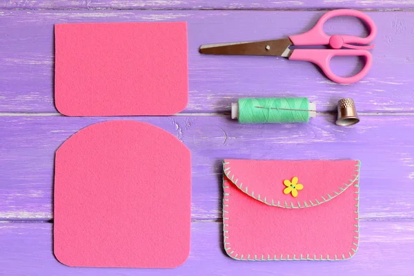 Children pink felt purse with yellow flower wooden button. Scissors, thread, needle, thimble on a wooden table. Easy homemade DIY made of felt. Top view — Stock Photo, Image