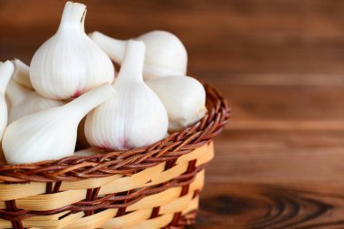 Metin için boş yer ahşap bir zemin üzerine bir hasır sepet genç sarımsak. Baharat sarımsak, sağlıklı gıda kavramı. Portre