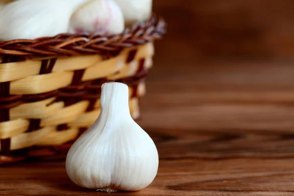 Fresh young garlic in a basket on a wooden background with copy space for text. Seasoning garlic, healthy and natural food. Closeup — Stock Photo, Image