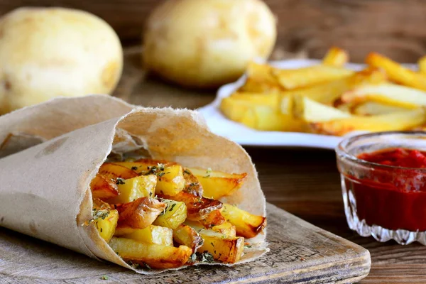 Baharatlı patates kızartması. Tatlı patates kızartması kağıt ve beyaz tabak pişmiş, baharatlı domates sosu, ahşap bir masa üzerinde ham patates. Portre