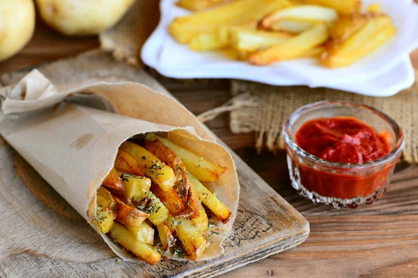 Çıtır çıtır patates kızartması. Kağıt ve kartonlar, ahşap içinde kavrulmuş tatlı patates kızartması. Domates sosu, ahşap bir masa üzerinde ham patates. Rustik tarzı