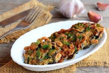 Sarımsak ve beyaz bir tabak ve bir çuval bezi Tekstil dereotu ile çıtır çıtır kızarmış patlıcan pirzola. Çatal ve bıçak vintage ahşap arka plan üzerinde. Gluten free kızarmış patlıcan pirzola tarifi. Portre