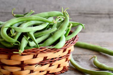 Hasır sepet içinde yeşil çalı fasulyesi. Taze genç fasulye bakla. Antika ahşap arka plan. Hasat kavramı. Portre