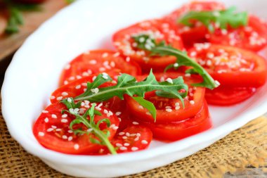 Domates ve Roka Salatası tarifi. Eve taze domates, beyaz bir tabak roka ve susam tohumu salataya. Hızlı ve sağlıklı vejetaryen salata tarifi. Portre 