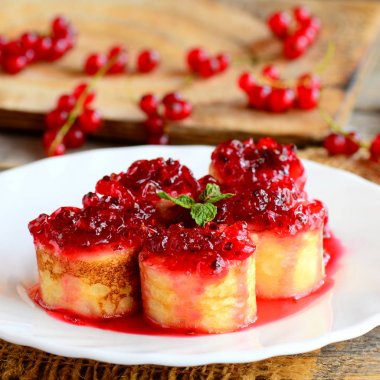 Tatlı kırmızı kuş üzümü reçeli ile krep. Ev yapımı krep rulo berry reçel ve nane yaprağı ile beyaz bir tabak ve eski bir ahşap masa üzerinde. Lezzetli yaz tatlı. Portre