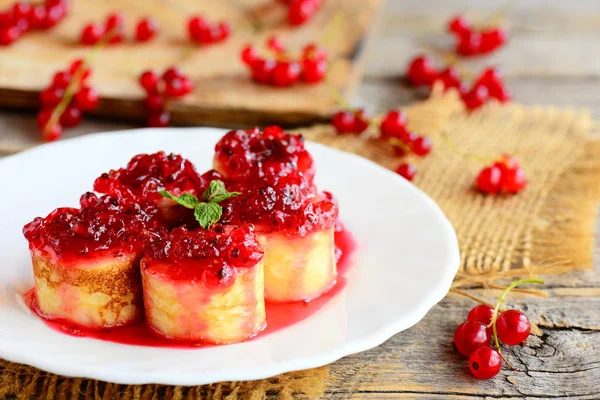 Stekt pannkakor med röda vinbär sås. Hemgjord pannkakor sushi på en vit platta och ett vintage träbord. Vacker och hälsosam frukost för barn och hela familjen — Stockfoto