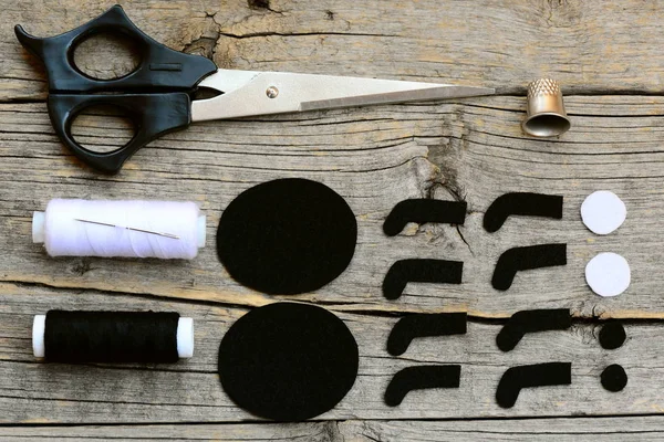 Corte detalhes de feltro preto e branco para criar decoração de aranha de Halloween. Passo. Tesoura, linha, agulha, dedal em um velho fundo de madeira. Halloween sentiu tutorial aranha costura. Vista superior. Fechar. — Fotografia de Stock