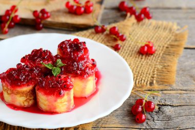 Ev yapımı gözleme suşi rulo somun ile beyaz bir tabak ve vintage ahşap bir masa üzerinde reçel. Doldurulmuş Krep tatlı tarifi. Sevimli Paskalya kahvaltı fikir