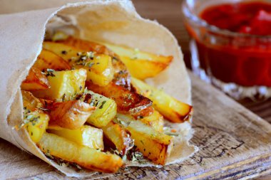 Kavrulmuş tuzlu patates kızartması kağıt ve bir masa, bir cam kapta domates sosu. Hızlı patates aperatif fikir