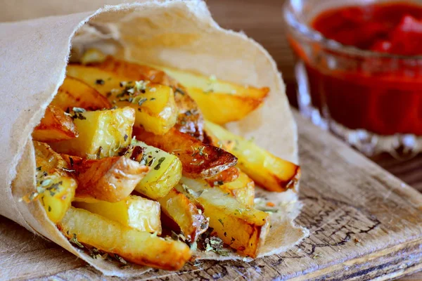 Kavrulmuş tuzlu patates kızartması kağıt ve bir masa, bir cam kapta domates sosu. Hızlı patates aperatif fikir
