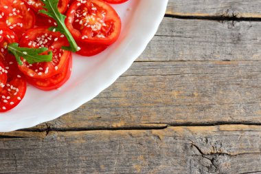 Domates, roka ve susam tohumu salata ev salata sos ile. Kolay domates salatası beyaz bir tabak ve eski ahşap arka plan metin için boş yer ile. Sağlıklı beslenme