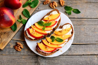 Sağlıklı kuru soğan, ceviz ve krem peynirli sandviç. Krem peynir, olgun kuru soğan dilimleri, ceviz ve nane bir beyaz plaka ve eski ahşap masa açık sandviçler. Yaz aperatif tarifi. Üstten Görünüm