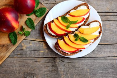 Yaz kuru soğan ve krem peynirli sandviç. Çavdar ekmeği açık sandviçle krem peynir, taze kuru soğan dilimleri ve nane bir beyaz plaka ve vintage ahşap masa. Yaz kahvaltı fikir. Üstten Görünüm