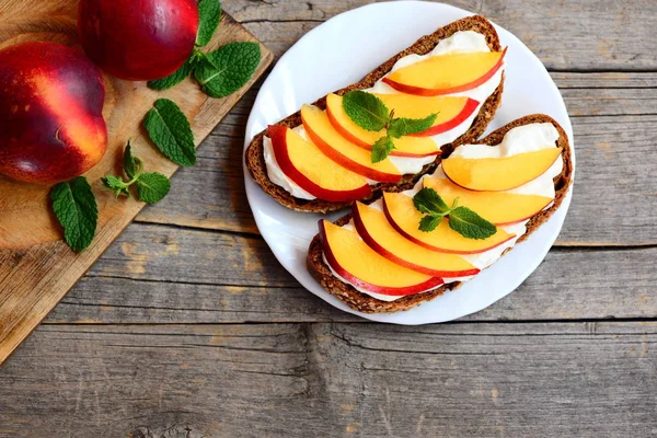 Yaz kuru soğan ve krem peynirli sandviç. Çavdar ekmeği açık sandviçle krem peynir, taze kuru soğan dilimleri ve nane bir beyaz plaka ve vintage ahşap masa. Yaz kahvaltı fikir. Üstten Görünüm