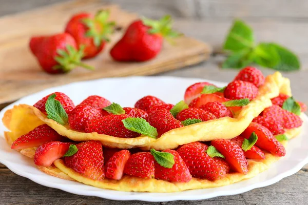 Hausgemachtes Omelett gefüllt mit frischen Erdbeeren auf einem weißen Teller. leckere und gesunde Eieromelette Rezeptidee. Frühstück. rustikaler Stil. Nahaufnahme — Stockfoto