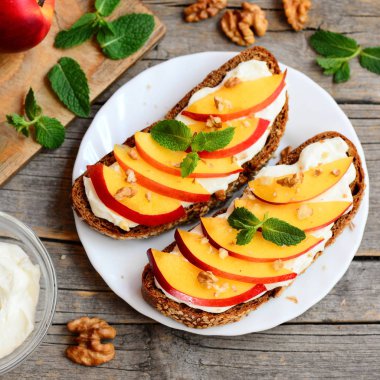Peynir, taze nektarin dilimleri ve ceviz ile kolay çavdar sandviç. Lezzetli yaz sandviç bir tabak ve vintage ahşap masa. Üstten Görünüm. Portre 