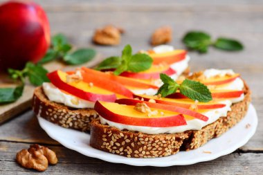 Krem peynir, taze nektarin, ceviz ve nane bir tabak ve vintage ahşap bir masa ile kolay sandviç. Çocuklar için krem peynirli sandviç tarifi. Rustik tarzı. Portre