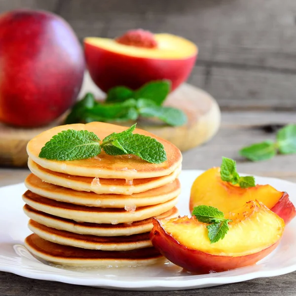 Leckere Pfannkuchen mit Sirup, Nektarine und Minze auf einem Teller. einfach Pfannkuchen Rezept für Kinder. rustikaler Stil. Nahaufnahme — Stockfoto