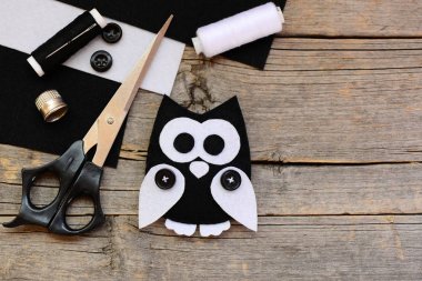 Doldurulmuş baykuş keçe oyuncak, sayfaları, makas, konu, kopya alanı vintage bir ahşap zemin üzerine düğmeler siyah ve beyaz hissettim. Çok güzel baykuş oyuncak keçe oluşturma. Baykuş el sanatları fikir çocuklar için. Üstten Görünüm