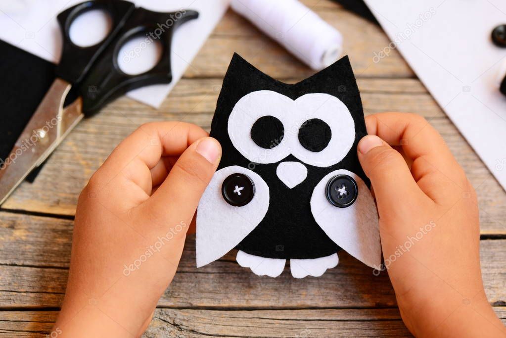 Small child holds a felt owl toy in his hands. Child shows a cute felt owl toy crafts diy. Teaching kids simple sewing skills at home during quarantine. Happy daycare kids. Kids activity background