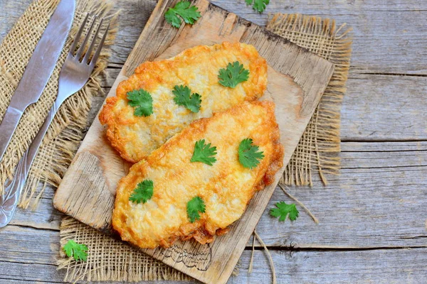 Gebratenes Hühnchen hacken Rezept. Leckere gebratene Hühnerhacken auf einem Holzbrett. Gabel und Messer auf einem alten Holztisch. rustikaler Stil. Ansicht von oben — Stockfoto