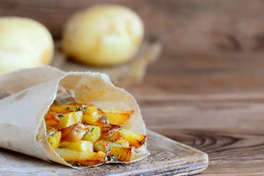 Baharat ile çıtır çıtır kızarmış patates. Ülke kızarmış patates kağıt ve ahşap bir masa. Rustik stile. Metin kopyalama yeri olan ahşap arka plan