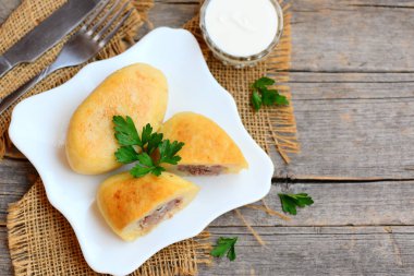 Kızarmış patates zrazy beyaz bir plaka üzerinde bir etli dolma. Ekşi krema, çatal, bıçak vintage ahşap bir masa üzerinde. Ev yapımı zrazy tarifi. Ahşap arka plan kopya alanı metin için ile. Üstten Görünüm