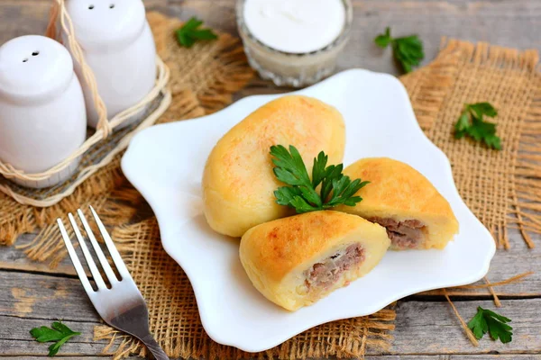 Kavrulmuş patates zrazy beyaz bir plaka üzerinde bir etli dolma. Ekşi krema cam kase, eski bir ahşap masa üzerinde çatalı. Ev zrazy tarifi. Portre