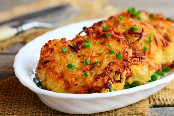 Panquecas de batata fritas ou draniki com fatias de presunto e cebola verde em uma chapa branca. Receita draniki simples. Fechar. — Fotografia de Stock