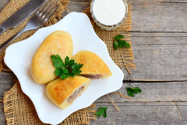 Kızarmış patates pirzola et ile doldurulmuş beyaz bir tabağa kıyma. Ekşi krema, çatal, bıçak eski ahşap masa. Ahşap arka plan kopya alanı metin için ile. Üstten Görünüm