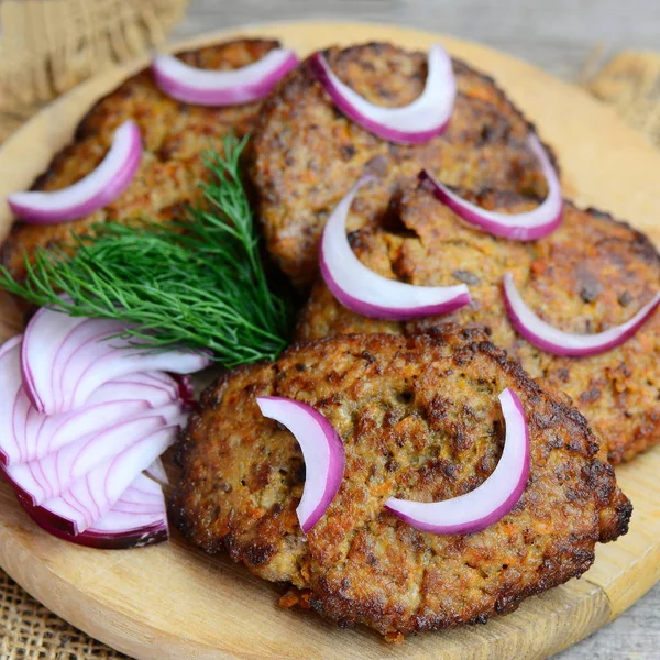 Домашние оладьи из куриной печени с овощами на деревянной доске. Жареная курица печени блины с морковью и луком. Простой рецепт печени. Сельский стиль. Крупный план — стоковое фото