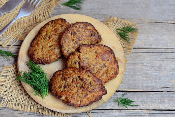 Chicken liver pancakes with vegetables on a cutting board and vintage wooden background with copy space for text. Fried chicken liver pancakes idea. Rustic style. Closeup