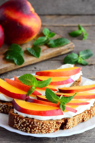 Krem peynir, nektarin ve nane bir servis tabağı ve vintage bir ahşap masa ışık sandviç. Çocuklar için sağlıklı sandviç tarifi. Dikey fotoğraf