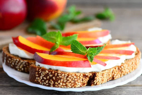 Krem peynir, taze nektarin ve nane bir tabak ve vintage ahşap bir masa ile basit sandviç. Çocuklar için krem peynir ve meyve sandviç tarifi. Rustik tarzı. Portre