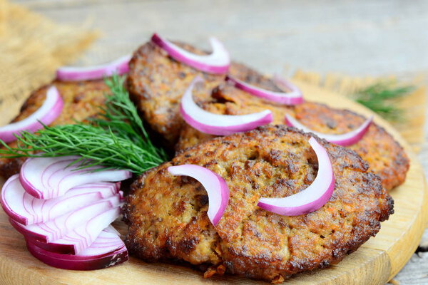 Fried cutlets made from chicken liver mince and vegetables. Fast simple liver cutlets on a wooden cutting board. Closeup