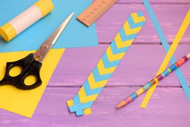 Sarı ve mavi yer işareti kağıt katlama yaptı. Sopa, kağıt sayfaları, cetvel, makas, yapıştırıcı kalem bir tablo. Nasıl kağıt ile basit bir yer işareti yapmak. Kağıt katlama ile çocuklar için kağıt el sanatları 