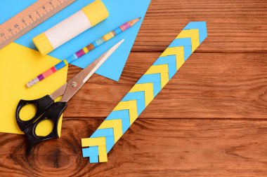 Kağıt kitap veya dizüstü bilgisayarlar için yer işareti. Okul öncesi ve okul için basit kağıt el sanatları. Cetvel, kalem, makas, yapıştırıcı sopa, renkli kağıt sayfalarının üstünde a okul sırası. Nasıl bir yer işareti yapmak. Üstten Görünüm