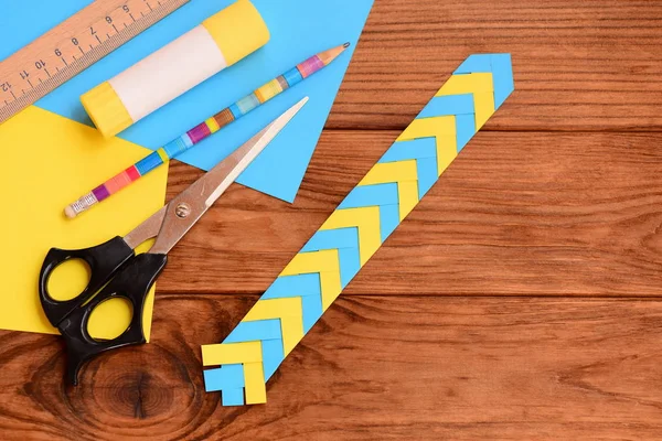 Kağıt kitap veya dizüstü bilgisayarlar için yer işareti. Okul öncesi ve okul için basit kağıt el sanatları. Cetvel, kalem, makas, yapıştırıcı sopa, renkli kağıt sayfalarının üstünde a okul sırası. Nasıl bir yer işareti yapmak. Üstten Görünüm